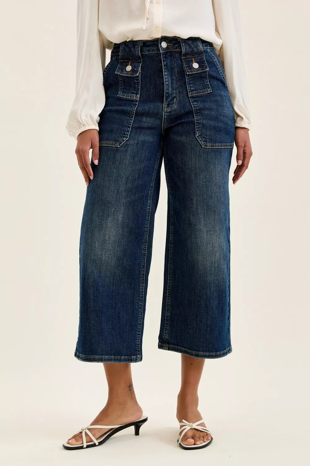 Person wearing dark blue wide-leg jeans on a plain background