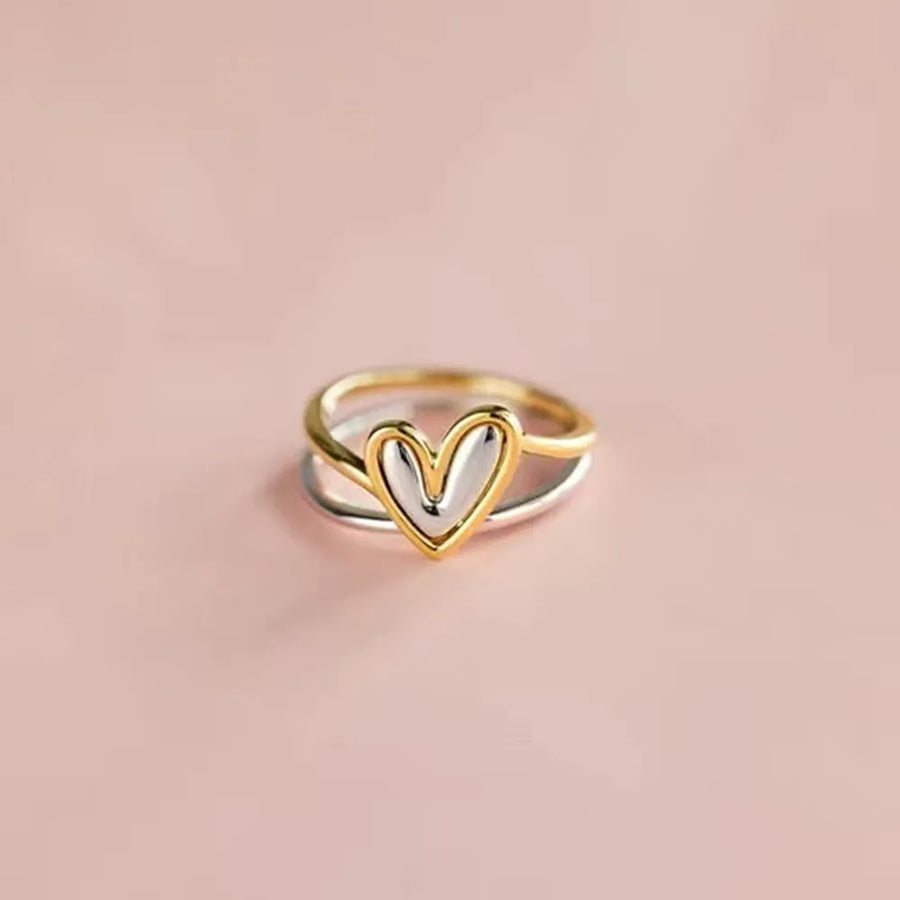 Two-tone heart-shaped ring on a beige background