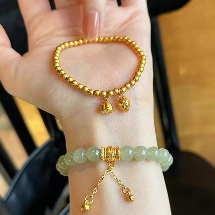 Gold and green beaded bracelets on a person's wrist with a blurred background