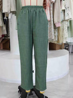 Green wide-leg trousers with an elastic waistband, displayed on a dress form mannequin in a clothing store.