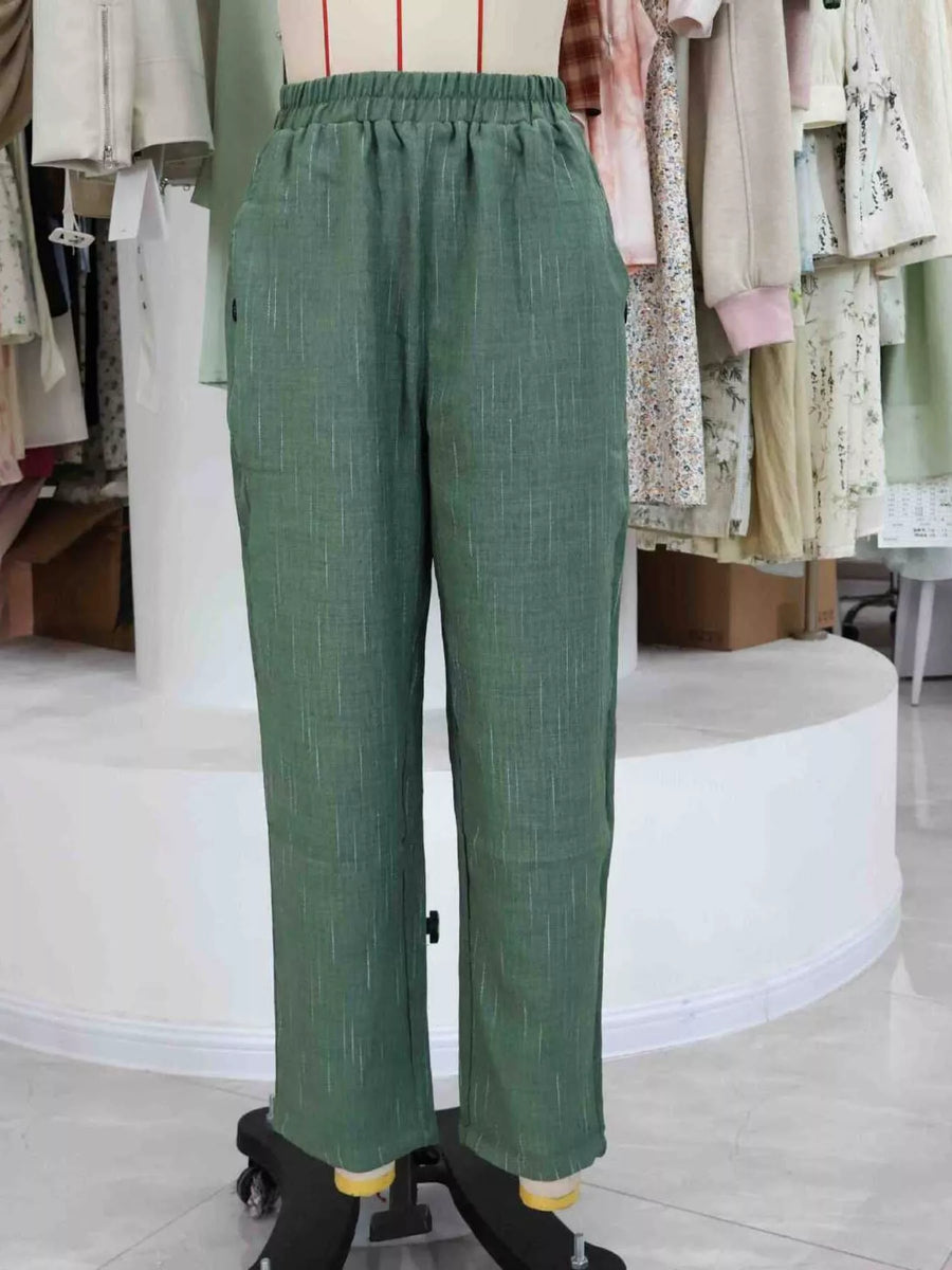 Green wide-leg trousers with an elastic waistband, displayed on a dress form mannequin in a clothing store.