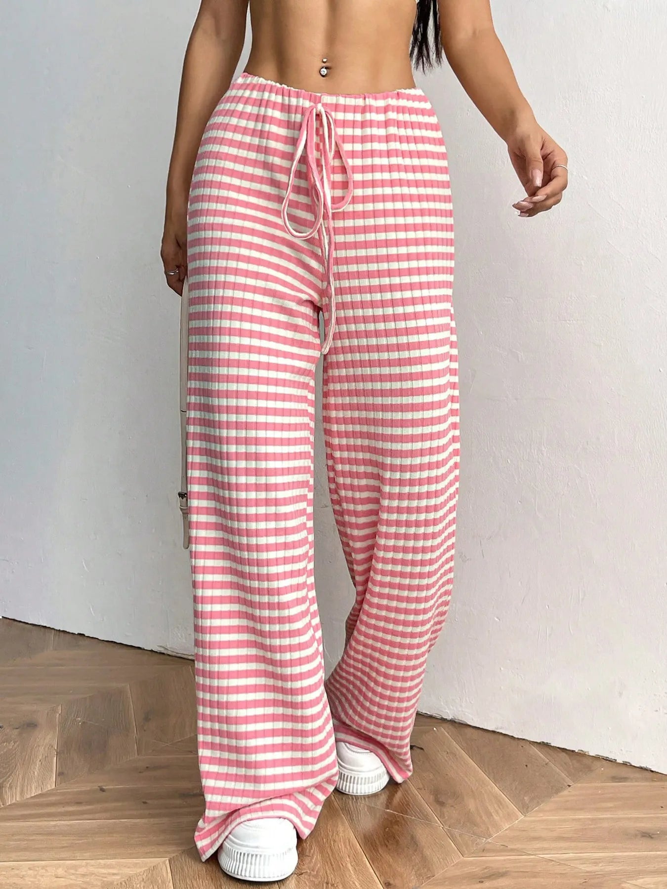 Person wearing pink and white striped pants on a wooden floor.