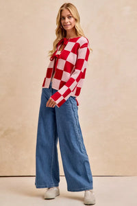 Woman wearing a red and white checkered shirt with blue jeans on a beige background