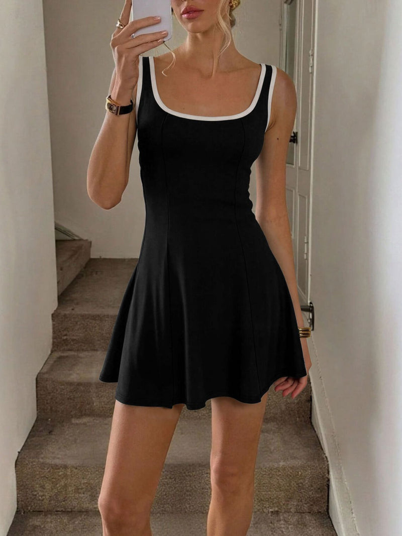 Person wearing a black dress taking a mirror selfie in a neutral setting.