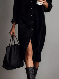 Person wearing a black dress holding a black bag against a gray background