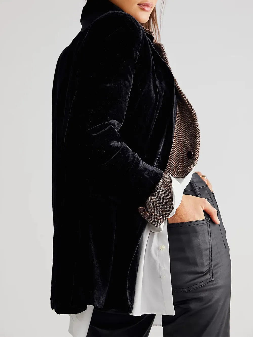 Person wearing a black velvet jacket over a patterned shirt on a white background