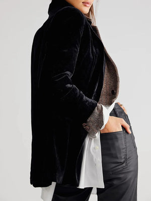 Person wearing a black velvet jacket over a patterned shirt on a white background