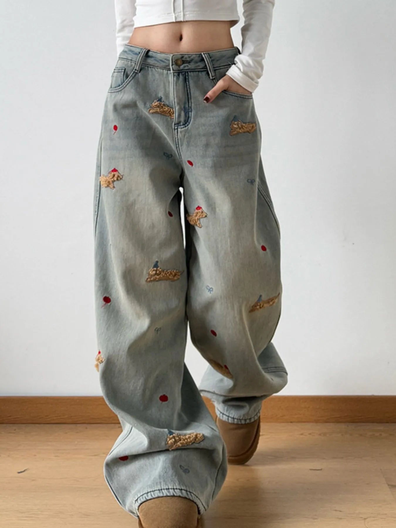 Light blue jeans with patches worn by a person on a plain background