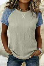 Person wearing a textured green and blue top with a blurred background