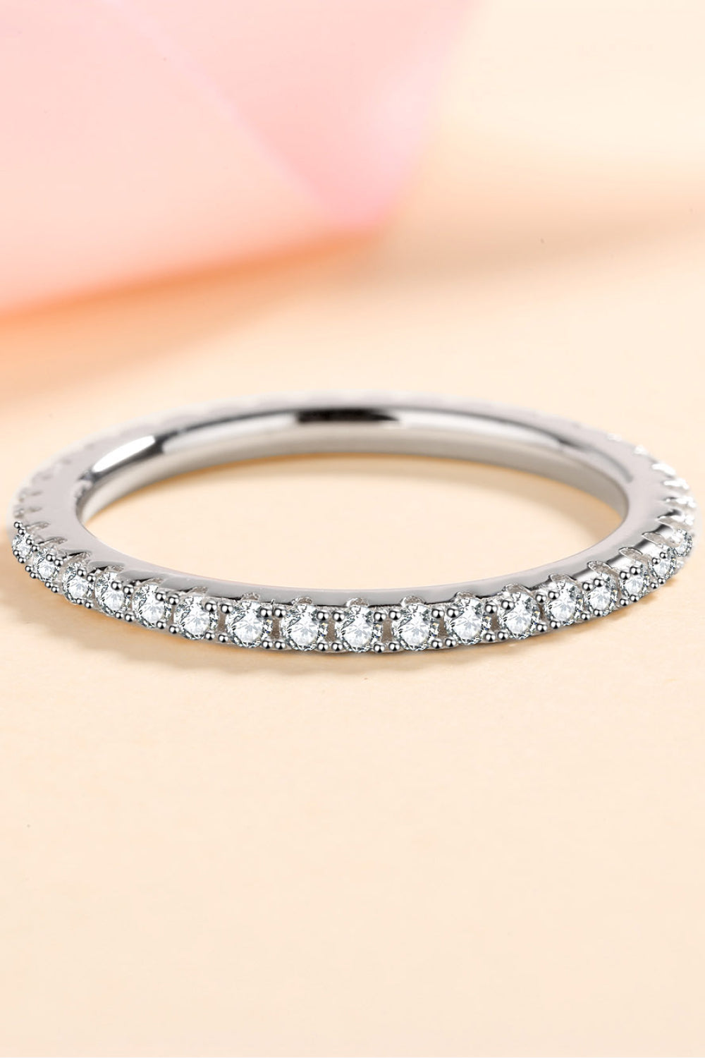 Silver ring with small diamonds on a soft pink background