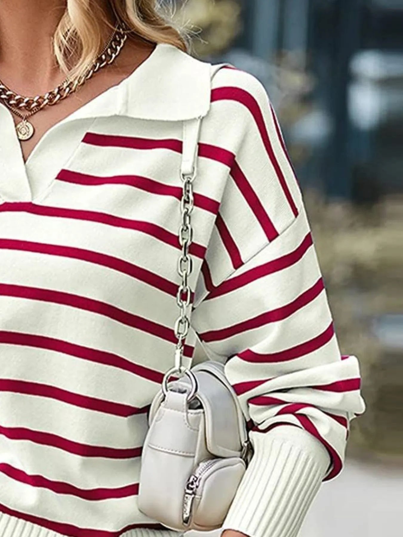 Person wearing a white and red striped sweater holding a white handbag.