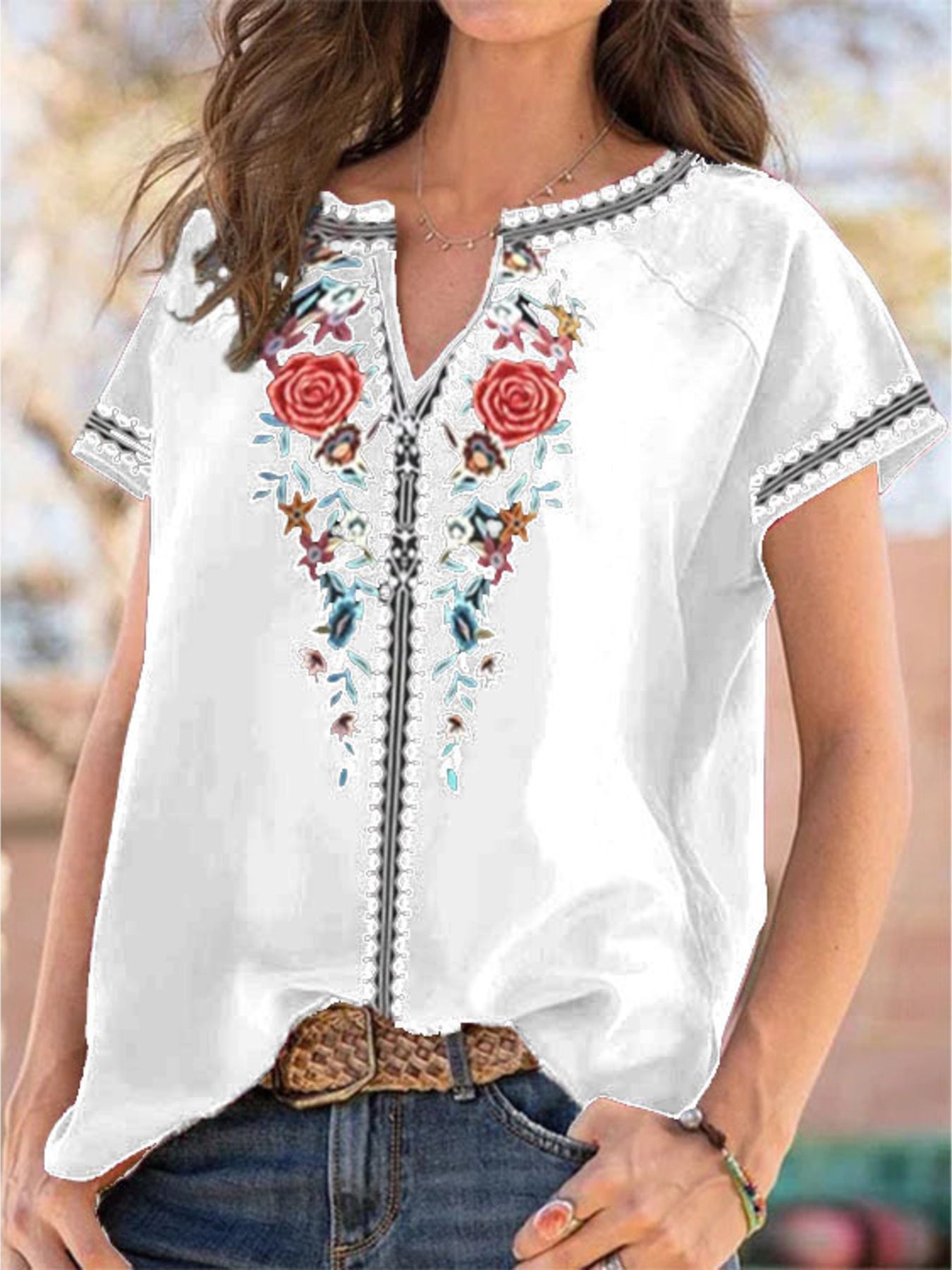 White blouse with floral embroidery and short sleeves worn by a person.