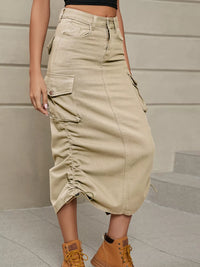 Person wearing a beige cargo skirt with pockets, standing against a neutral background.
