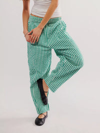 Green and white checkered pants worn by a person on a plain background