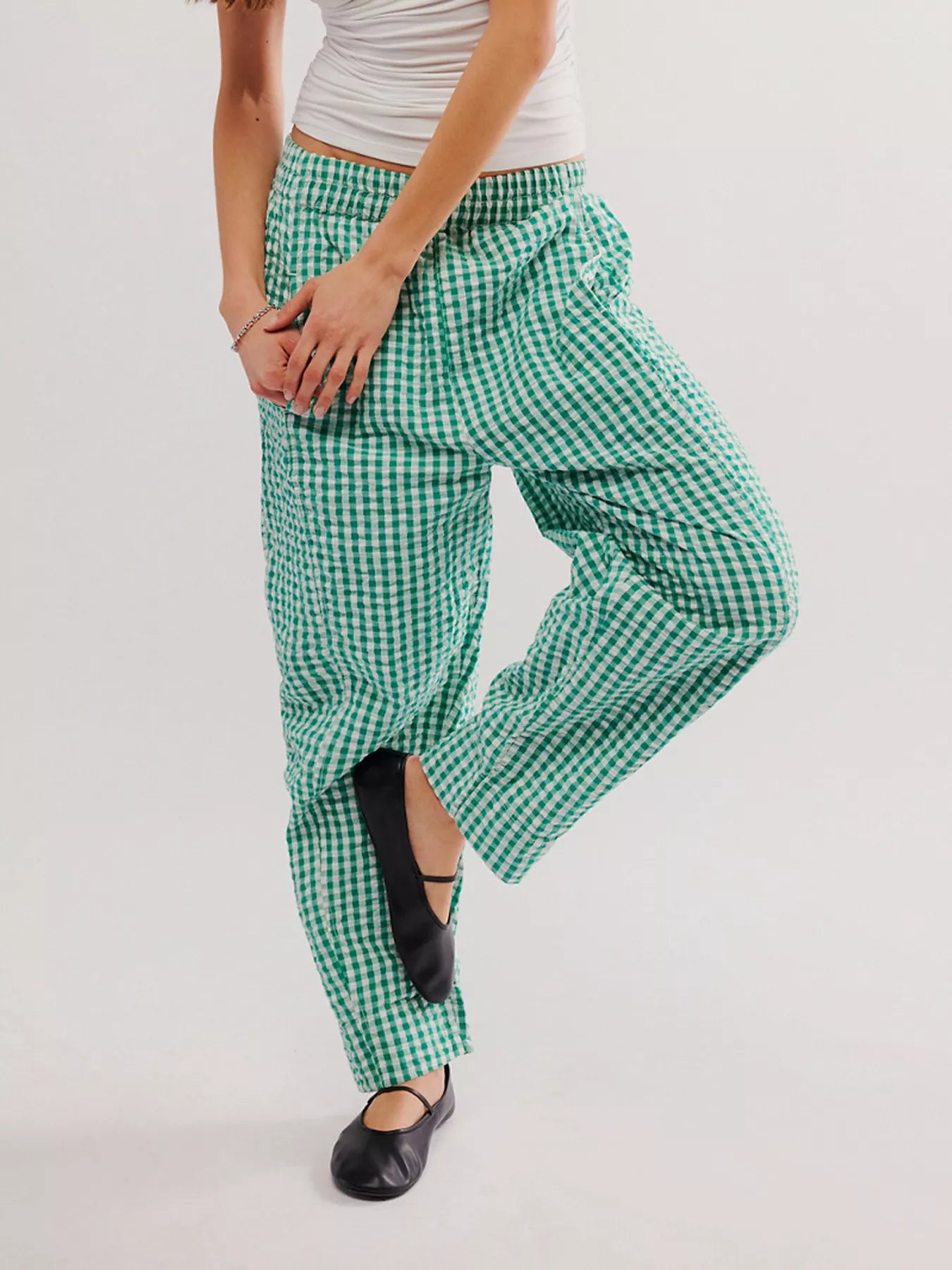 Green and white checkered pants worn by a person on a plain background