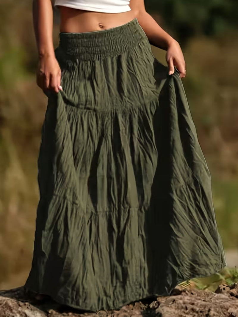 Person wearing a long green skirt with a blurred natural background