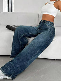 Person wearing blue jeans sitting on a white couch.