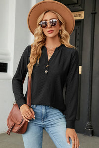 Woman wearing a black long-sleeve top, blue jeans, and a brown hat with sunglasses outdoors.