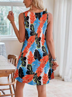 Woman wearing a colorful leaf-patterned dress indoors.