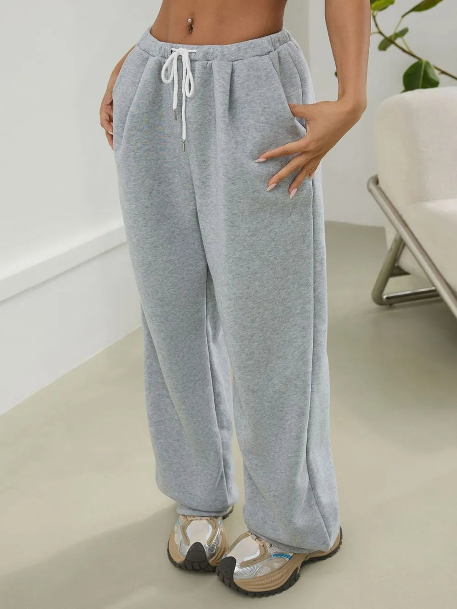 Person wearing gray sweatpants in a minimal indoor setting