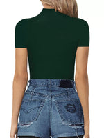 Person wearing a dark green turtleneck and blue jeans on a white background