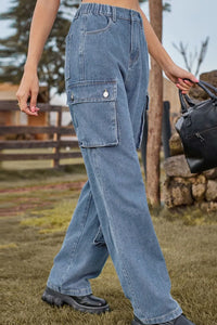 Person wearing blue jeans holding a black bag outdoors.