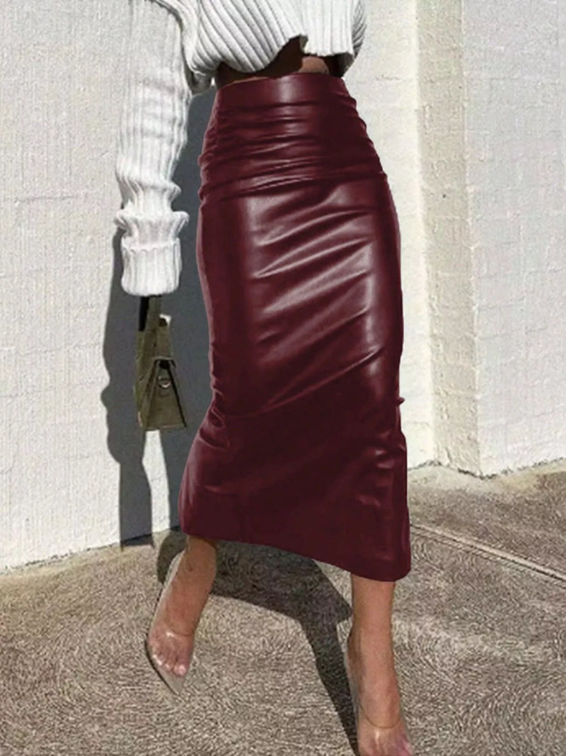 Person wearing a burgundy leather skirt with a white top against a light-colored wall.