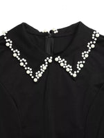 Black garment with a decorative white pearl collar on a white background