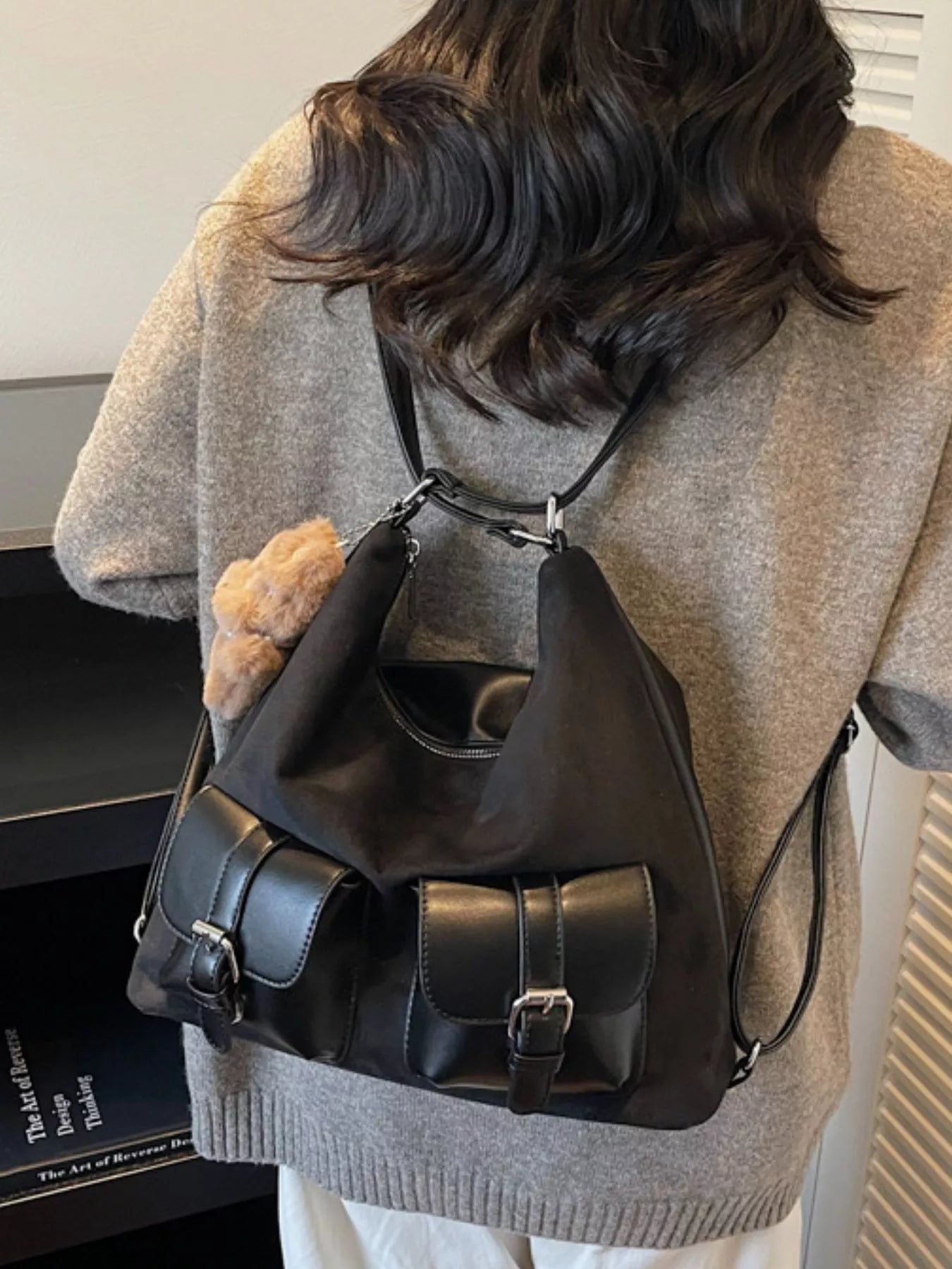 Person wearing a black backpack with a neutral background