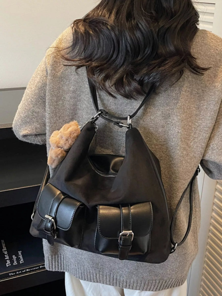 Person wearing a black backpack with a neutral background