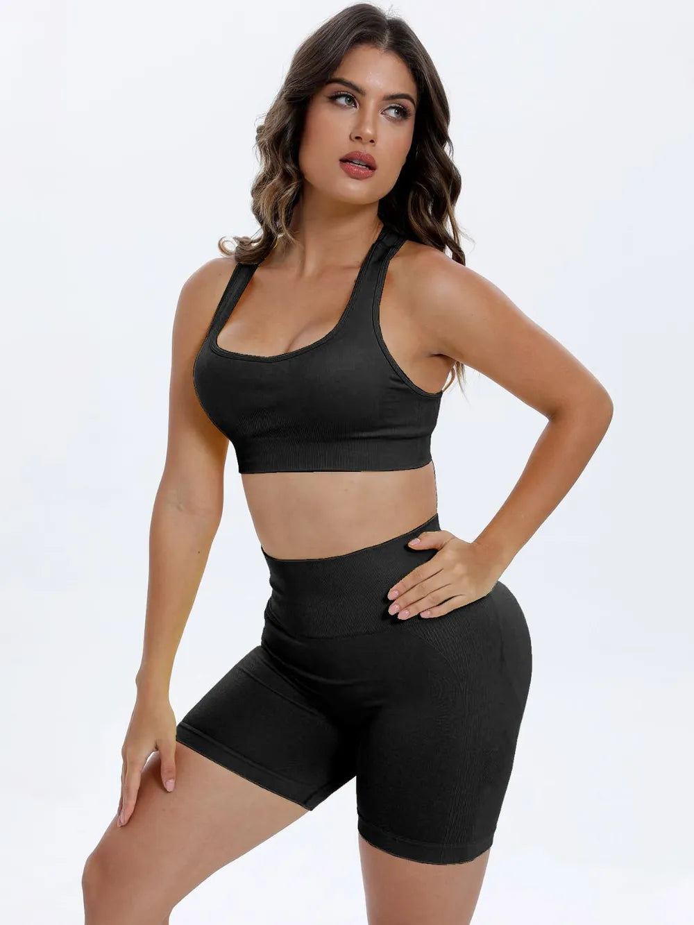 Woman wearing a black sports bra and shorts on a white background