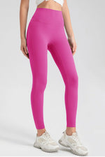 Person wearing bright pink leggings and white sneakers on a light gray background