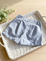 Blue and white striped shorts on a wicker tray with a plant in the background