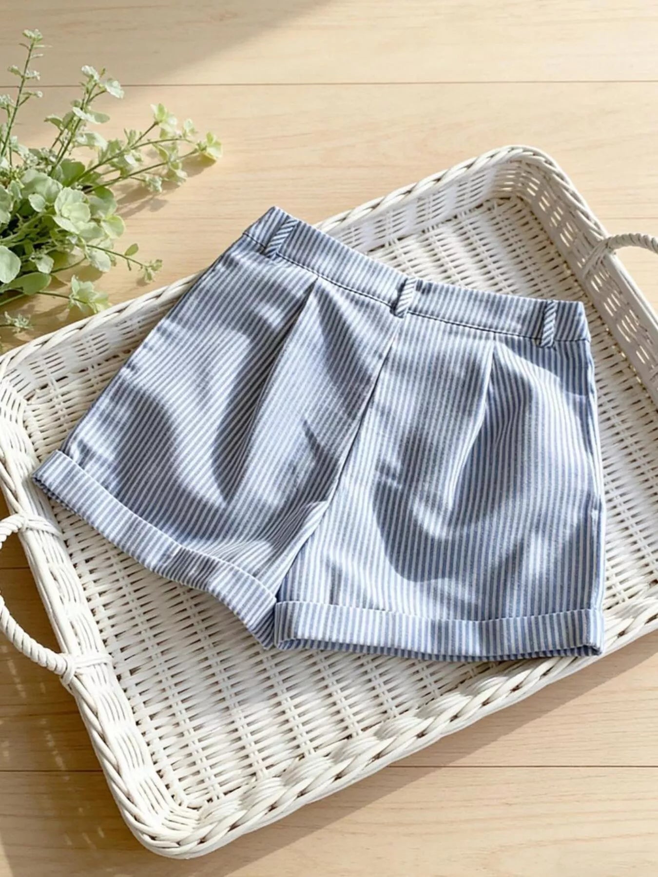 Blue and white striped shorts on a wicker tray with a plant in the background