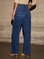 Person wearing blue jeans with a neutral background