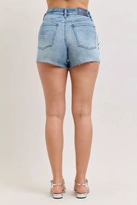 Light blue denim shorts worn by a person on a plain background