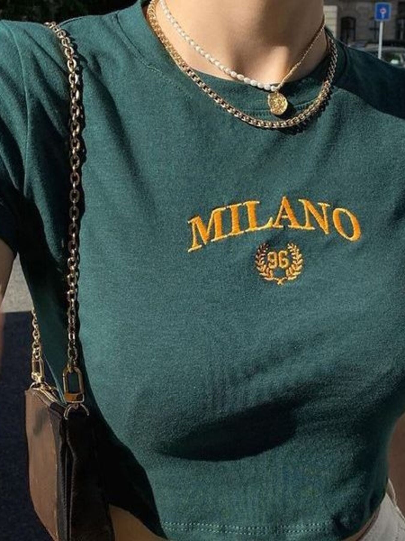 Green t-shirt with 'MILANO 96' text and design, worn by a person.