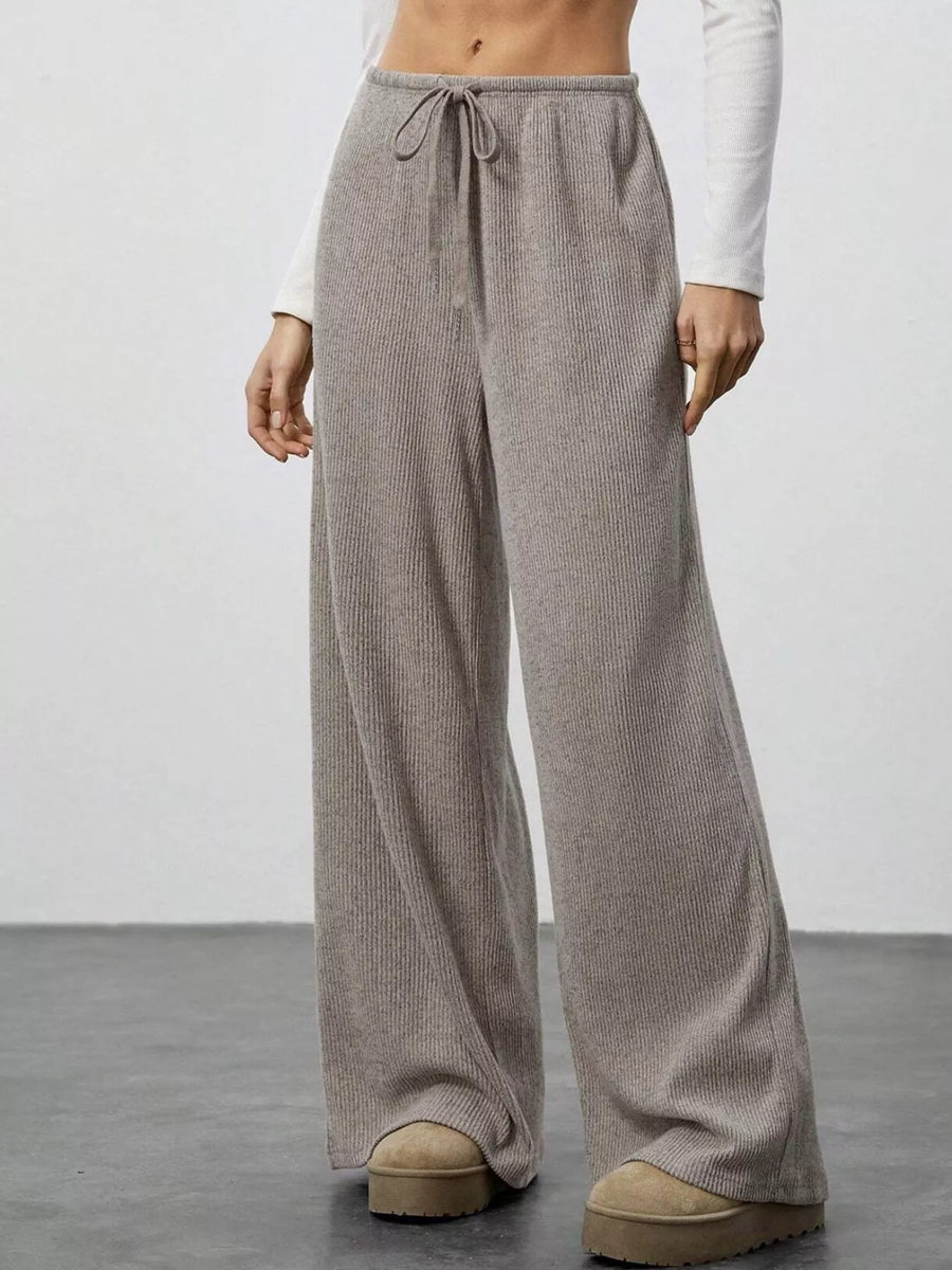 Person wearing beige wide-leg pants with a plain background