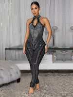 Woman in a sparkling black jumpsuit standing in an elegant room.