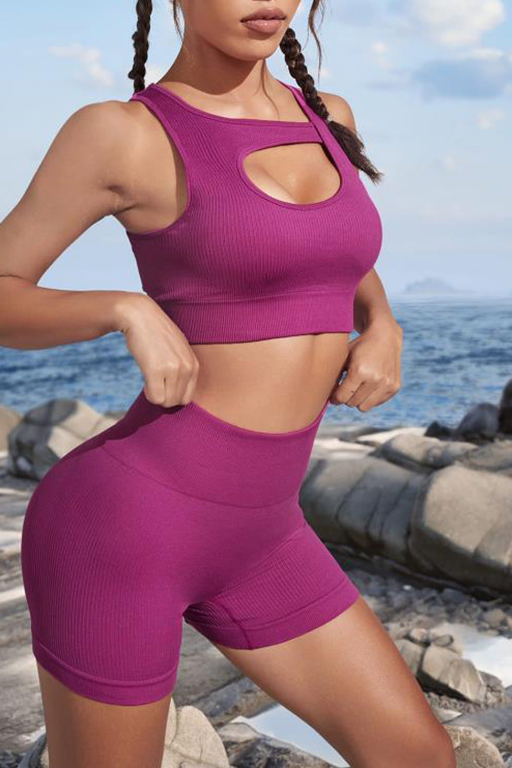 Person wearing a purple athletic outfit standing on a rocky beach.