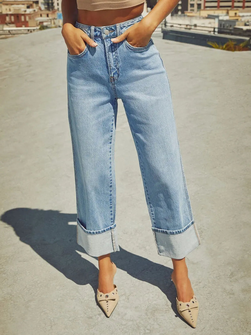 Person wearing light blue jeans and beige shoes on a rooftop.