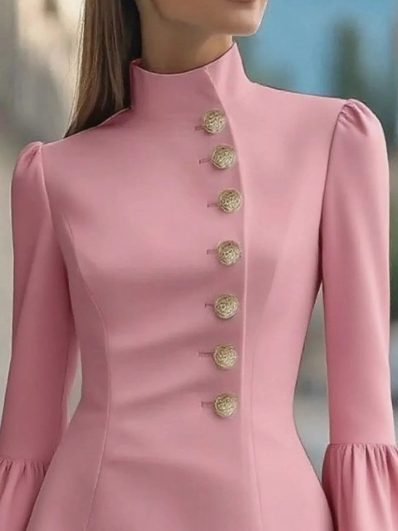 Close-up of a pink dress with gold buttons on a blurred background