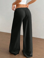Person wearing black wide-leg pants against a plain background