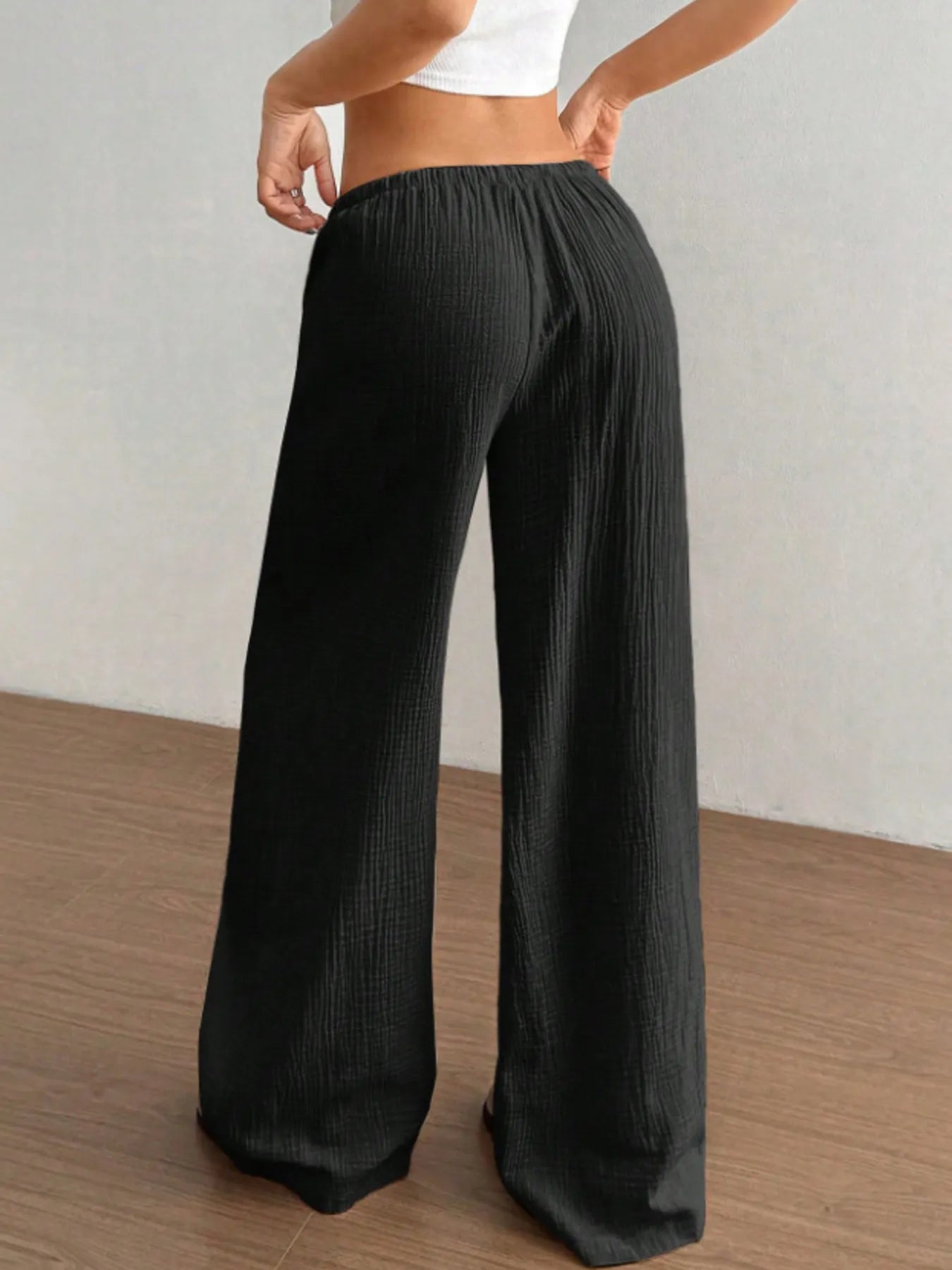 Person wearing black wide-leg pants against a plain background