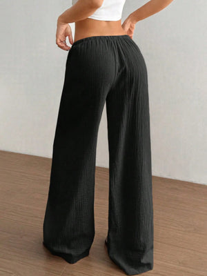 Person wearing black wide-leg pants against a plain background
