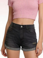 Person wearing black denim shorts and a pink crop top on a plain background