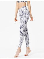 Person wearing white leggings with purple floral pattern on a white background