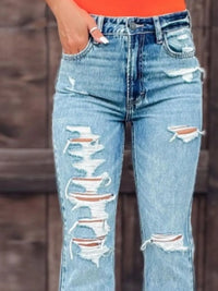 Ripped blue jeans worn by a person against a blurred background