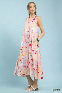Woman wearing a light pink dress with colorful patterns on a light blue background