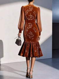 Brown embroidered dress worn by a model against a white wall